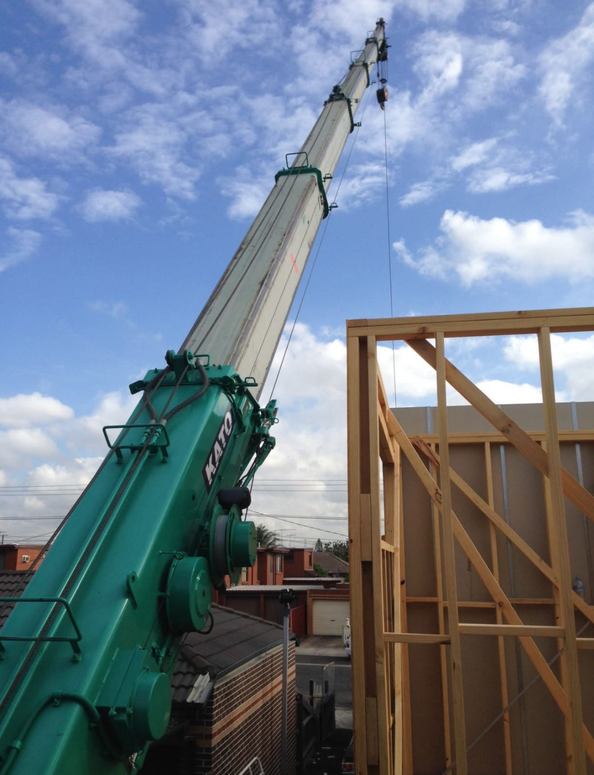 Hudson crane services mobile crane lifting materials onto a timber-framed build